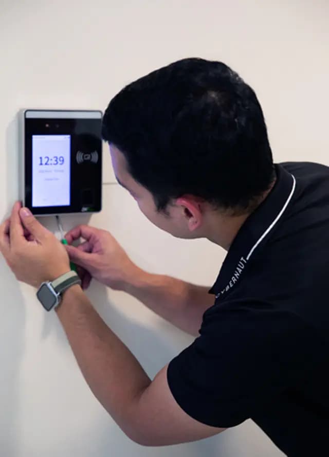 Technician installing a wall-mounted digital biometric face recognition time attendance terminal