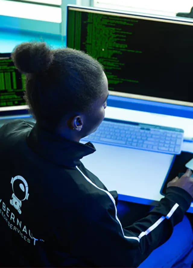 A network security professional works at a multi-monitor workstation